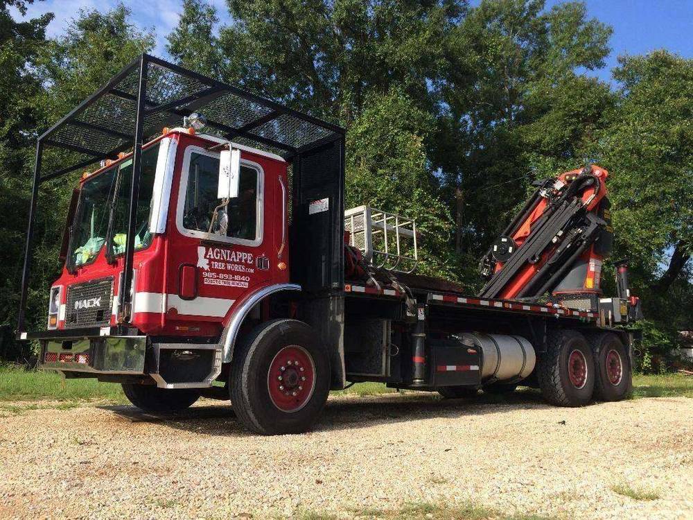Red Mack flatbed with the folded knuckleboom crane parked at the Bush shop yard